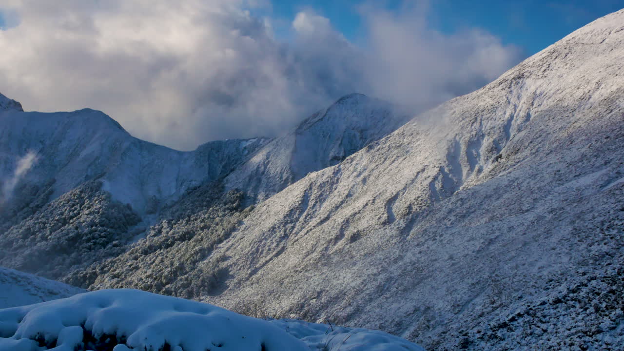 toma panorámica de hermosas montañas nevadas rodeadas de nubes a la luz del sol durante una caminata en la pista kepler en nueva zelanda