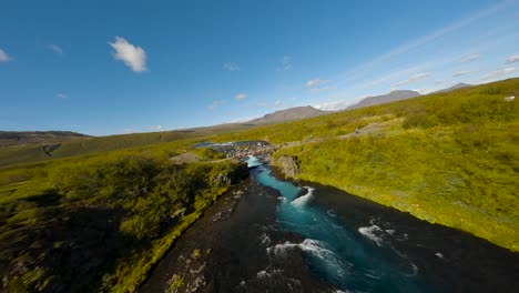 aerial establishing fpv shot of tourists standing on a bridge at a beautiful river