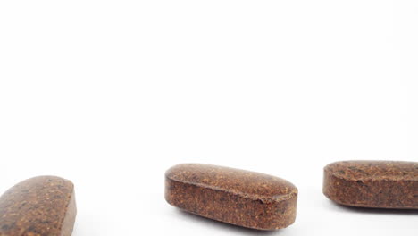 minimalistic view of herbal brown tablets scattered on white surface