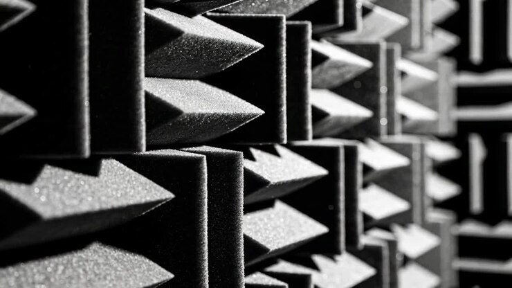 Moving camera revealing pyramidal acoustic foam wall in sound-treated room, highlighting dust