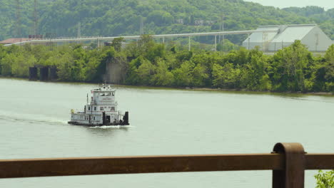 a tugboat cruising along the river in an industrial are of pennsylvania