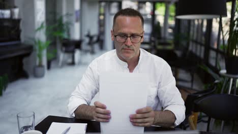 hombre de negocios adulto concentrado trabajando en un proyecto, escribiendo notas en papel, sentado en el escritorio de un café. concentrado profesional masculino