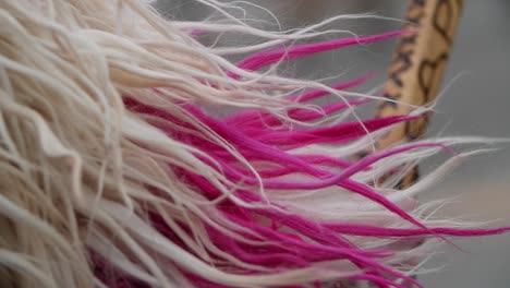 hebras de lana blanca y rosa rebotando mientras el kuker búlgaro hace una danza tradicional