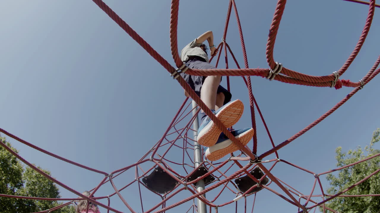 Brave boy and girl climbing rope attraction in park
