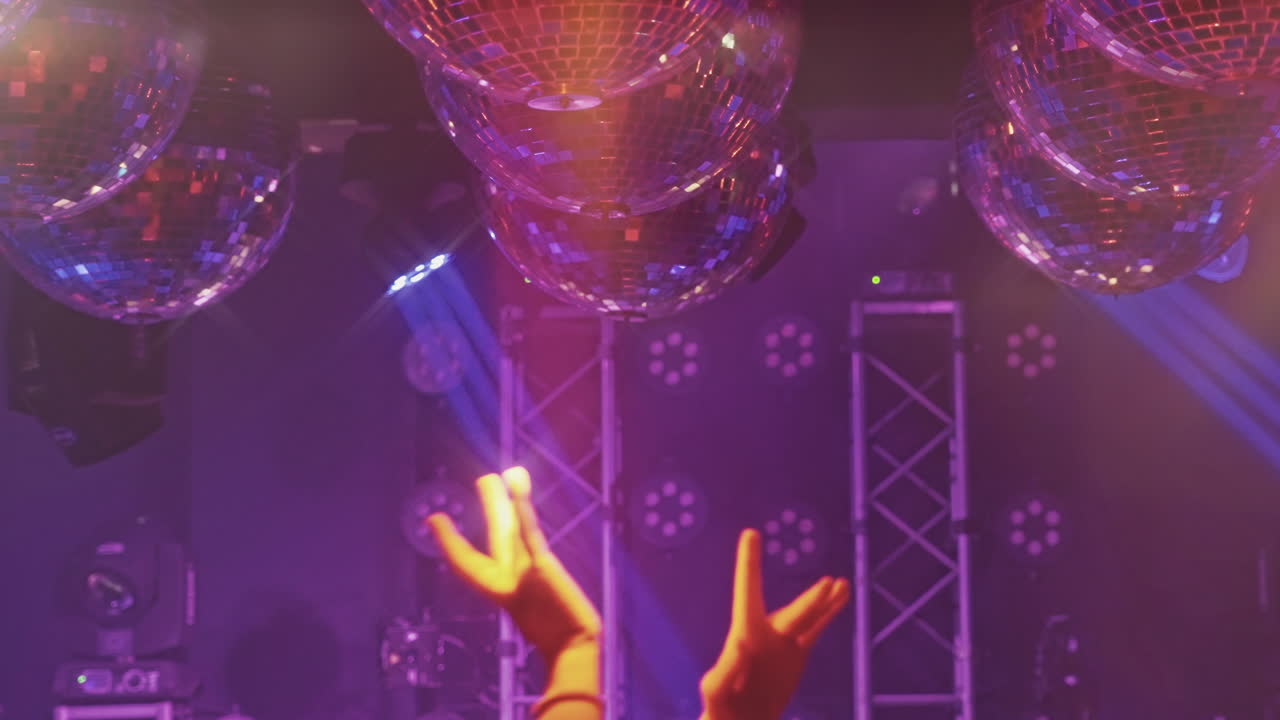 Mani danzanti sotto sfere da discoteca e luci vibranti del club