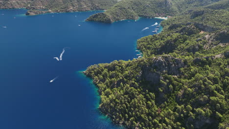 barcos de vela y motos acuáticas en el océano frente a la costa de turquía