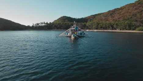 vuelo aéreo a través de la toma de un pequeño barco de pasajeros estacionado cerca de una isla en palawan, filipinas