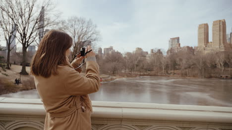 woman taking pictures of central park in winter