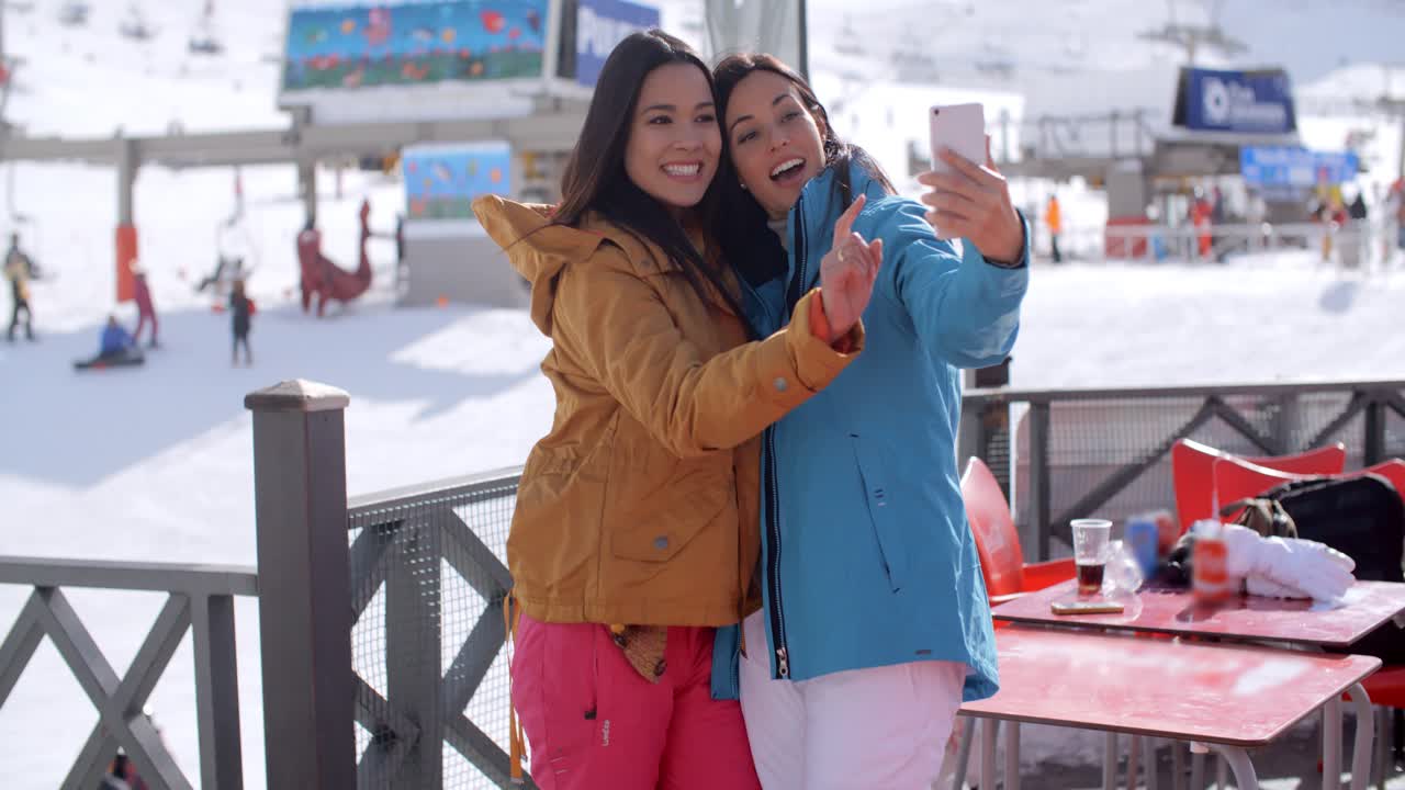 amigos riendo tomando una selfie en una estación de esquí