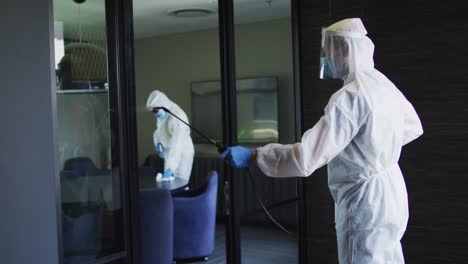 equipo de trabajadores de la salud con ropa de protección limpiando la oficina usando rociador desinfectante