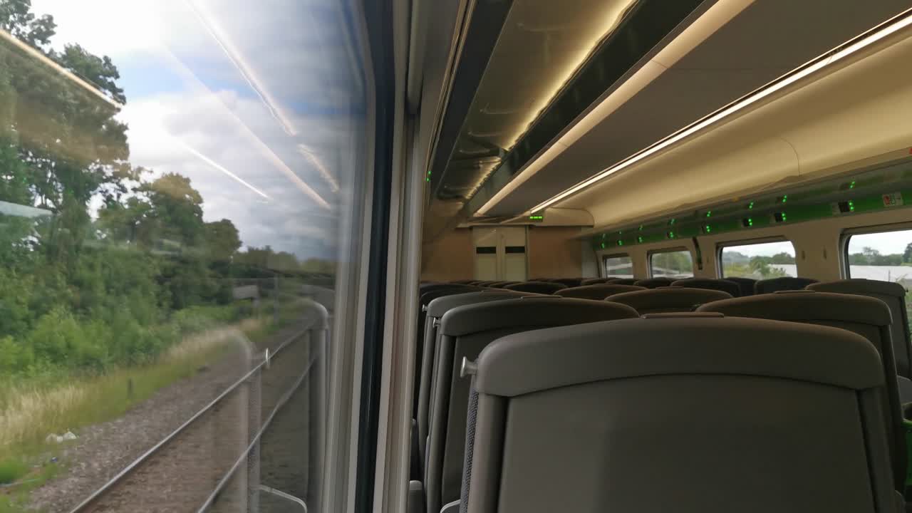 una vista de un tren británico vacío que viaja con una vista desde dentro de un vagón de tren y parcialmente la vista exterior desde la ventana del tren