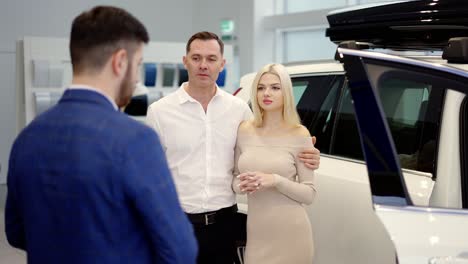 portrait couple talking to car dealer in dealership discussing the chosen car