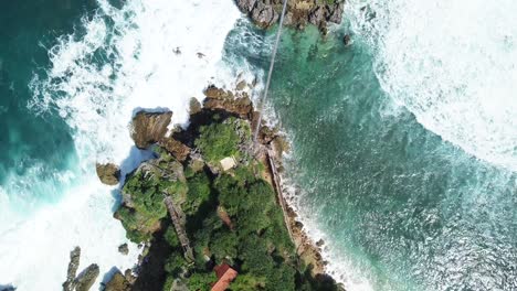 drone flight looking down on the cliffs of timang coral island yogyakarta indonesia where the ocean waves break foaming on the rocks of the shores