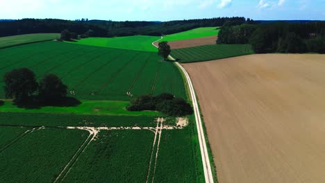 aerial-shot-of-plowed-farmland-and-green-fields,-4k