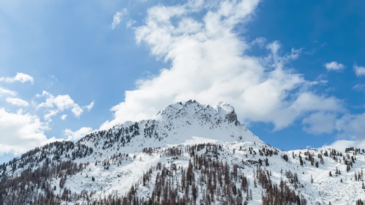 Maloja Geçidi'nin karla kaplı dağ manzarası, parlak mavi bir gökyüzü ve bulutlarla. Havadan hiperlaps.