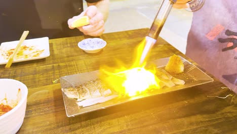 chef uses blowtorch to sear fish fillets