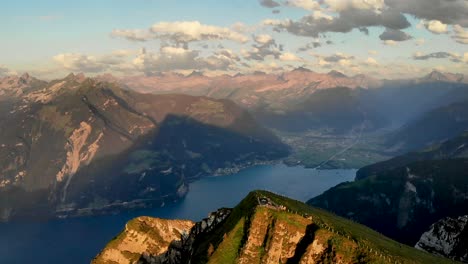 sobrevuelo aéreo lejos de la cumbre de niederbauen chulm que revela los acantilados del pico con vistas a los fiordos de uri y el lago lucerna en el fondo en una tarde de verano en los alpes suizos