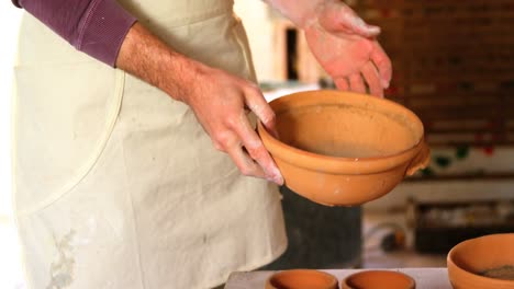 male potter checking bowl in pottery workshop