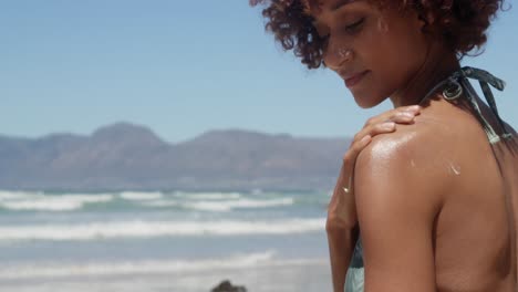 woman applying sunscreen on shoulders at beach in the sunshine 4k