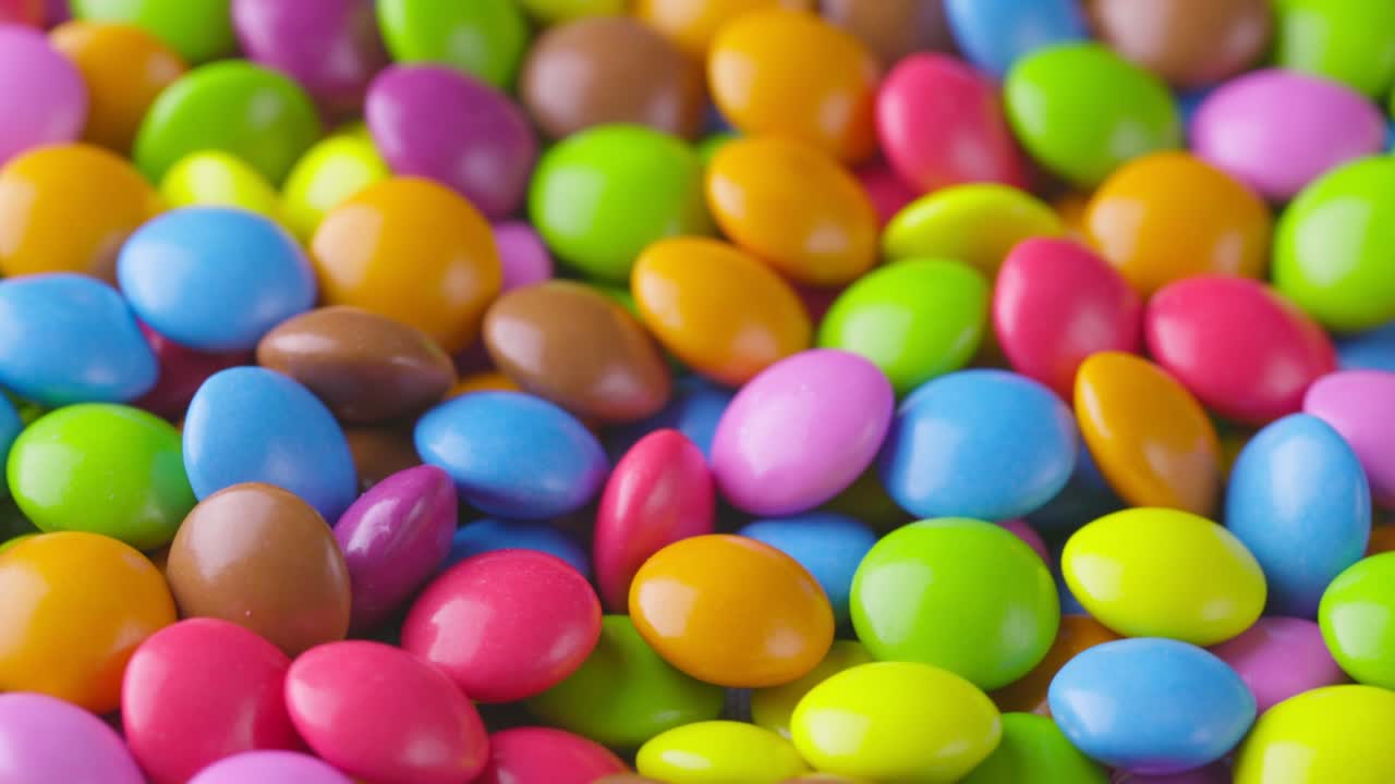 movimiento lento de primer plano de caramelos de chocolate redondos de colores, dragee. rotación y caída de caramellos de chocolate multicolores