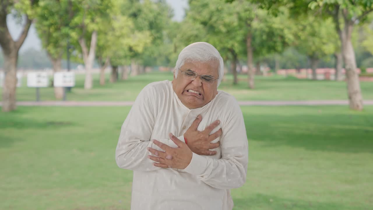 Sick Indian old man having a heart attack in park