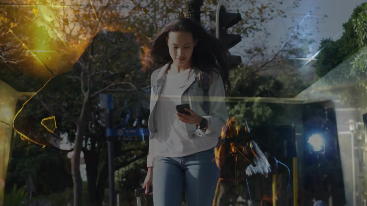 Después de que el semáforo se pone en verde, una mujer sube a la acera arrastrando una bolsa, utilizando tecnología móvil para navegar su ruta.