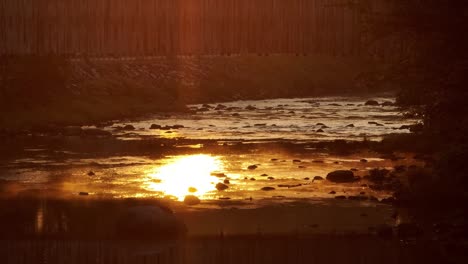 spectacular golden hour sunset reflected in river tilt-up reveal shot