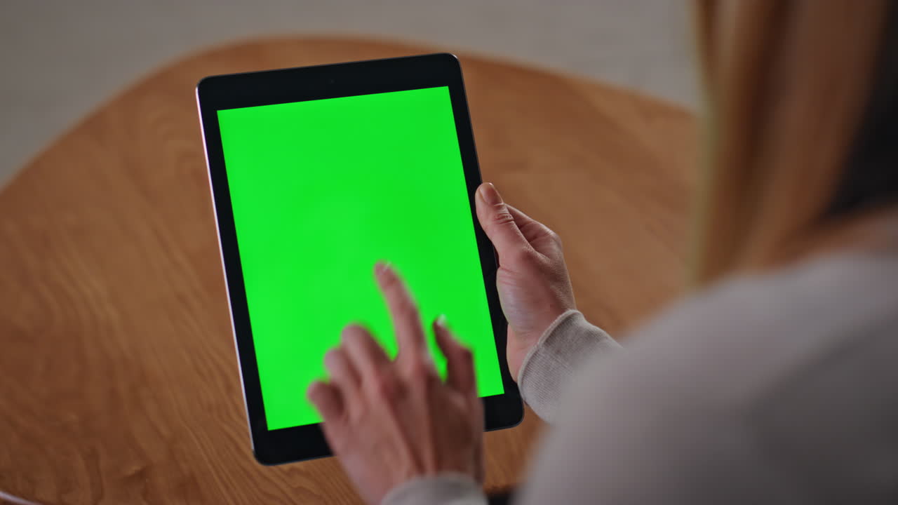 Unrecognizable businesswoman swiping green screen tablet at home close up.