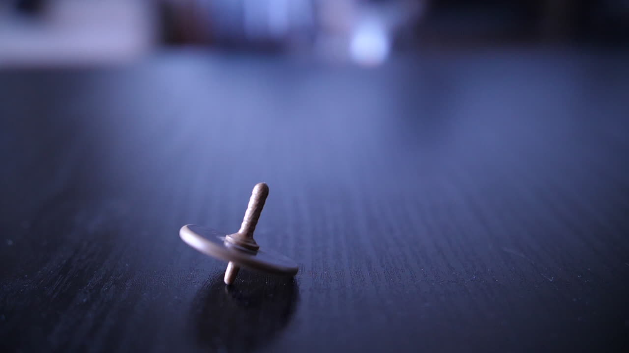 Close-up of a Spinning Top Wobbling on a Dark Table