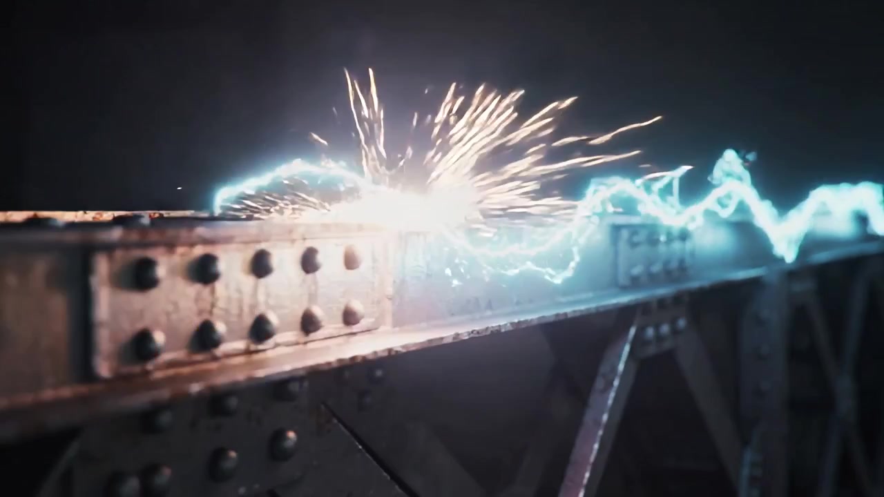 Un arco elettrico impetuoso che contatta la flangia sinistra, tracciando una trave rivettata in studio e creando scintille arancioni.