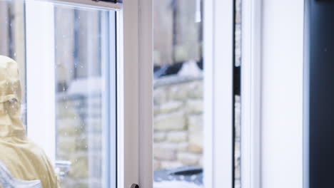 woman in yellow coat with fur hood looking out window