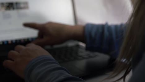 Busy-woman-pointing-at-laptop-screen-in-office-over-the-shoulder-close-up-shot