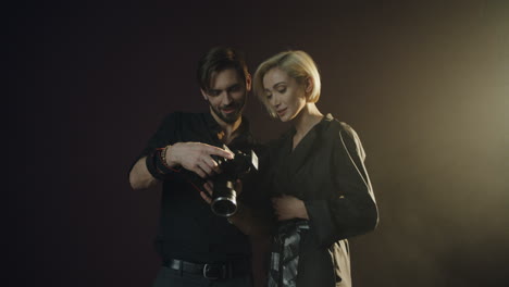 Close-up-view-of-caucasian-male-photographer-and-female-model-watching-photos-on-the-camera-screen-in-dark-studio