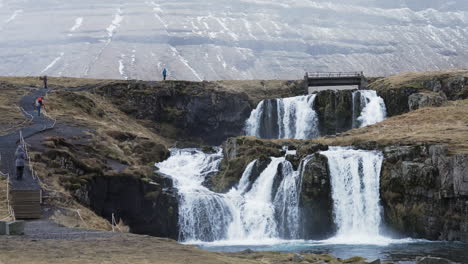 gran vista de la cascada con turistas, kirkjufell, islandia