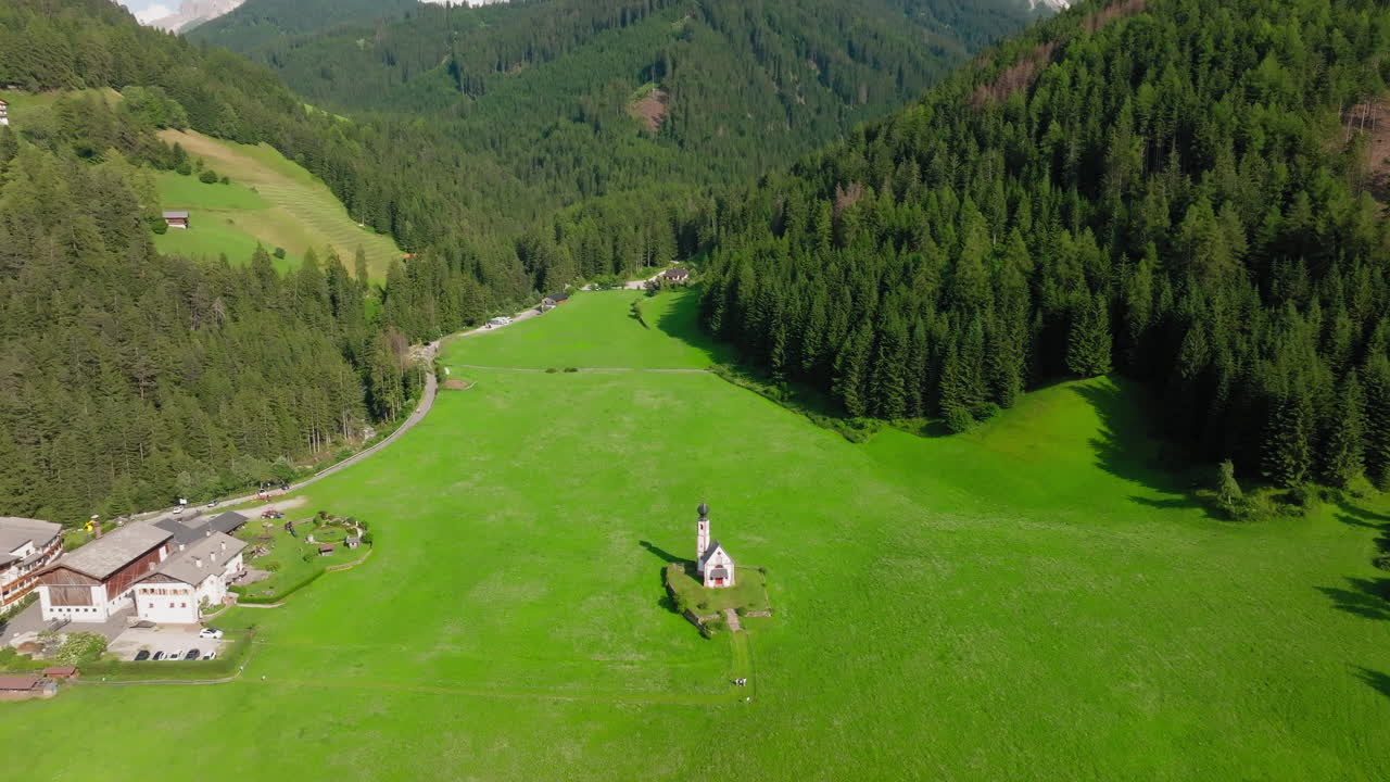 Aerial video of San Giovanni Church in the Dolomites, nestled in blooming alpine meadows during spring, Dolomites, Ranui