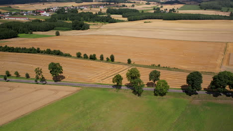 Cars-travelling-down-the-countryside-road,-peaceful-rural-farming-land