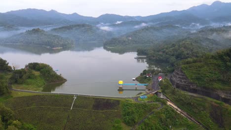 aerial view of dam with beautiful view of misty forest and hill