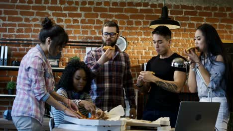 colleagues in office eating pizza together