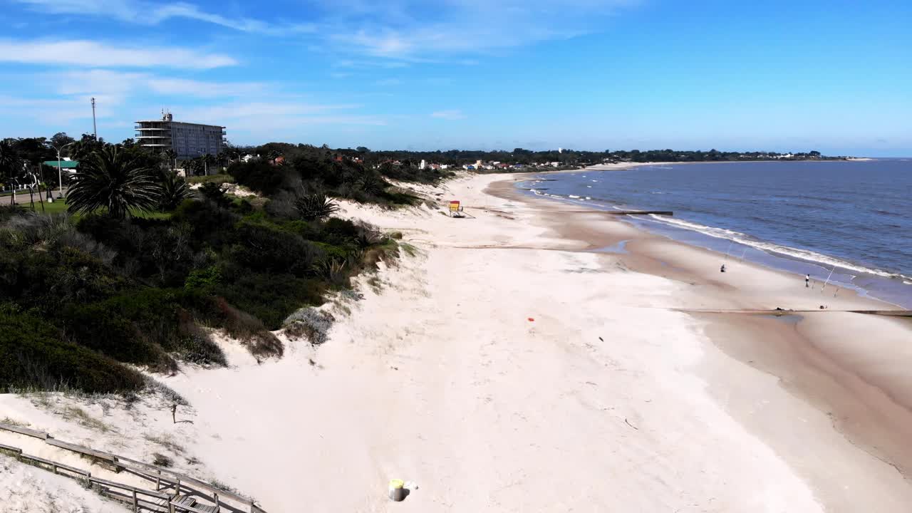 video aéreo que baja por la costa en la playa en un día soleado