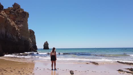 playa praia dos tres irmaos, algarve, portugal - chica turista caminando en la playa de arena a través del mar azul claro