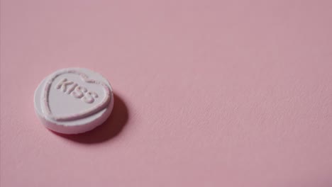 mano recogiendo caramelos de corazón con beso de palabra sobre fondo rosa