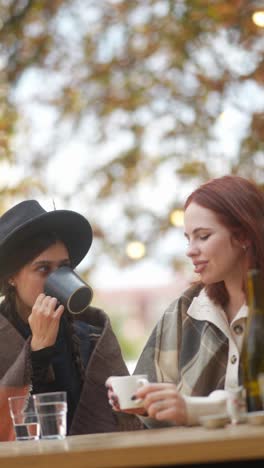 two women enjoying coffee outdoors in autumn