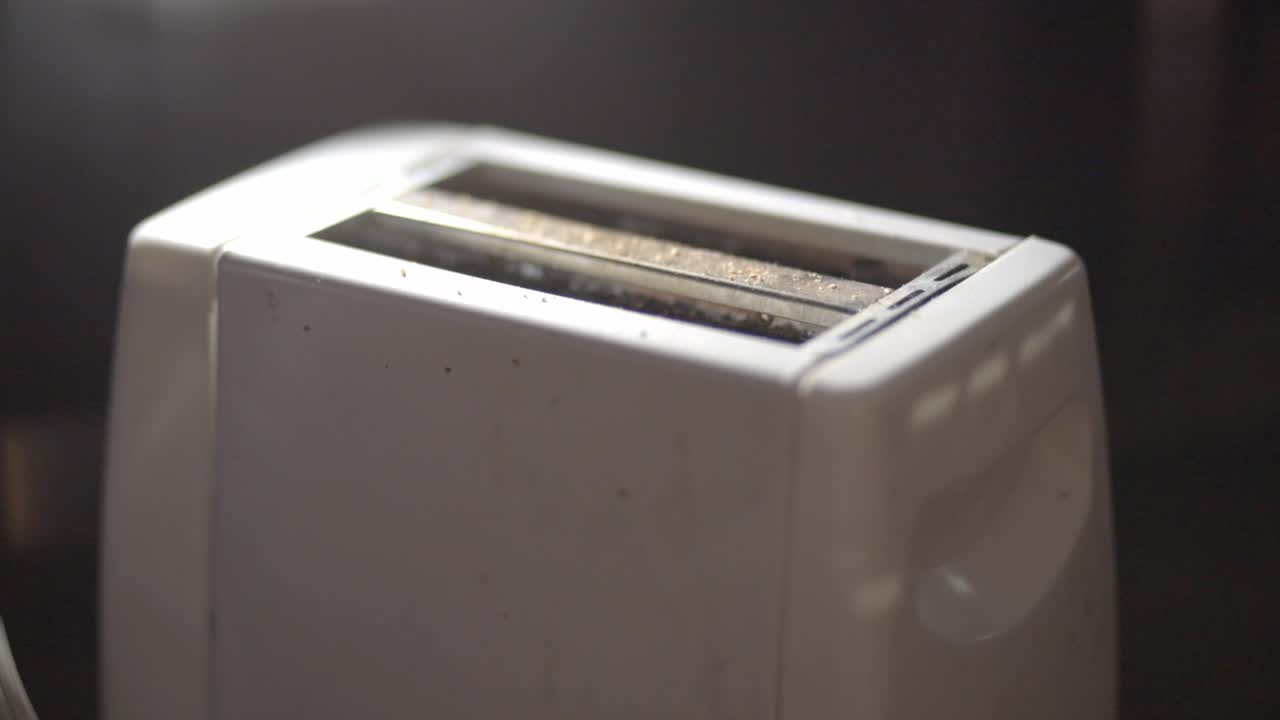 Person Making A Toasted Bread Using A White Toaster For Breakfast In The Kitchen