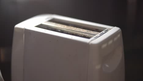 Person-Making-A-Toasted-Bread-Using-A-White-Toaster-For-Breakfast-In-The-Kitchen