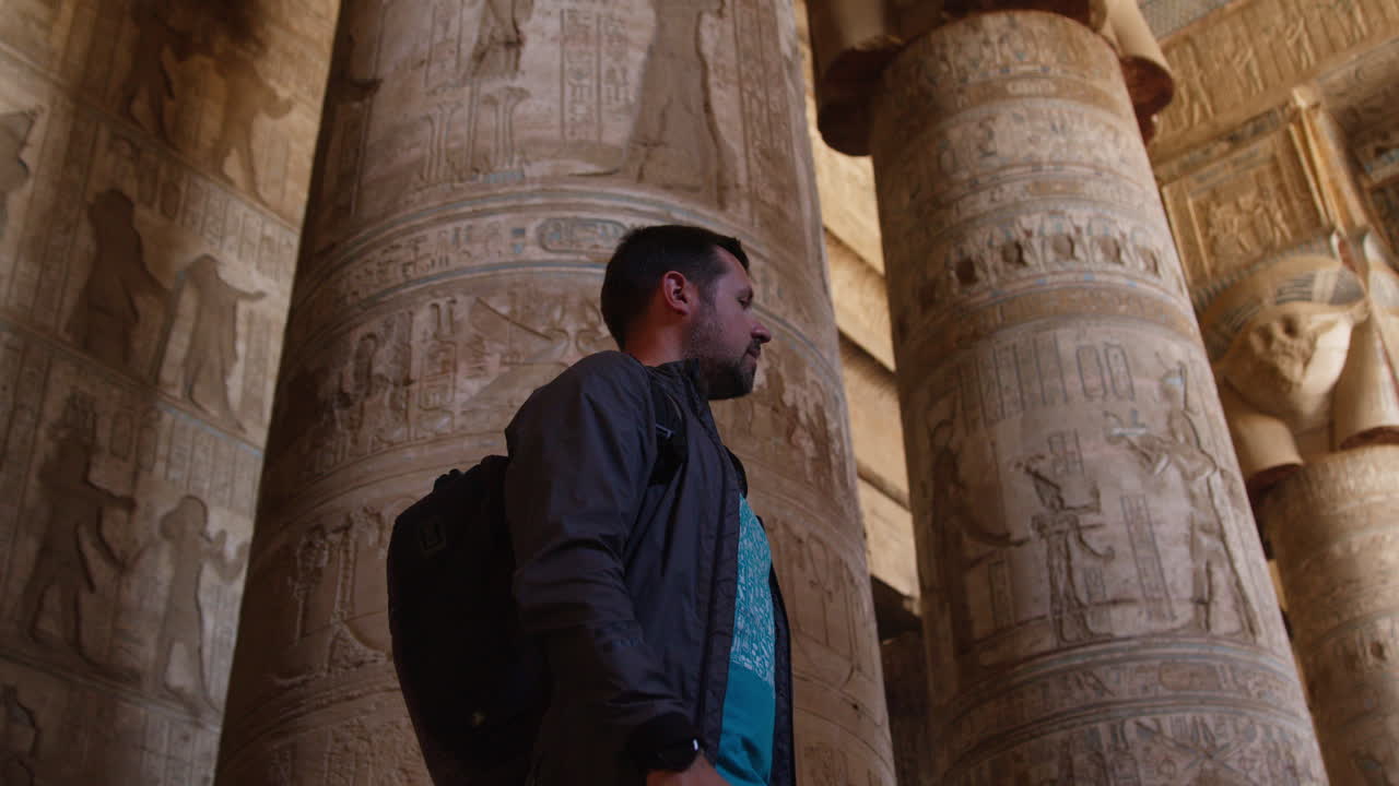 Man admiring ancient temple pillars with carvings, Dendera, Egypt, interior view