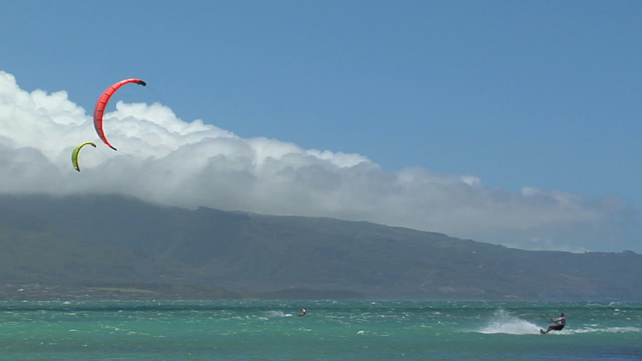 una toma amplia de un windsurfista contra un paisaje hawaiano