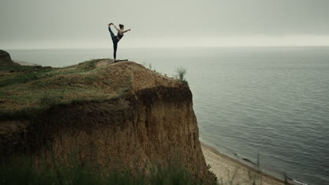 Mujer-Atleta-Estirándose-Sosteniendo-La-Pierna-En-La-Colina-De-La-Playa.-Chica-Practicando-Yoga-Cerca-Del-Mar