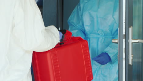 a courier in a protective suit hands the doctor a red case with valuable medicines 1