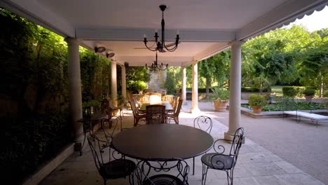 a beautiful terrace with roman columns and wrought iron tables, set in a castle garden