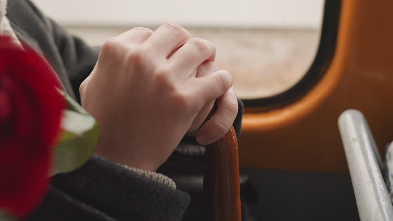 Scena descrittiva dettagliata. Persona che afferra un manico di legno con anelli. Individuo nervoso che tiene un bastone vicino a una rosa in fiore con anelli. Primo piano di una persona che giocherella con un accessorio vintage vicino alla finestra.